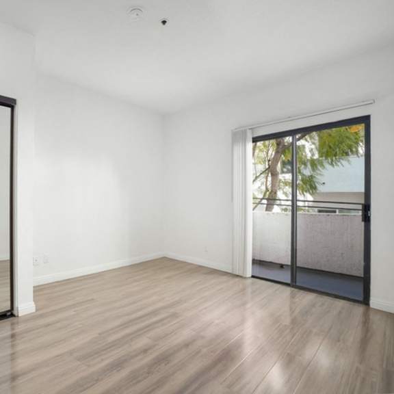 Thumbnail 8 of 11 A room with a sliding glass door leading to a balcony.