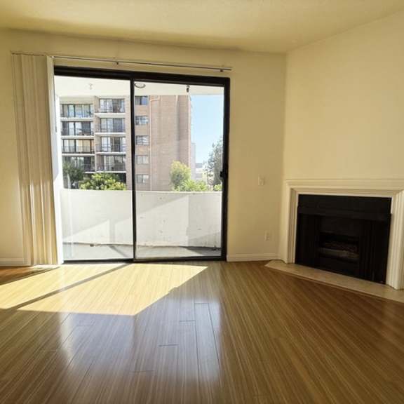 Thumbnail 18 of 18 A large, empty room with a fireplace and sliding glass doors leading to a balcony.