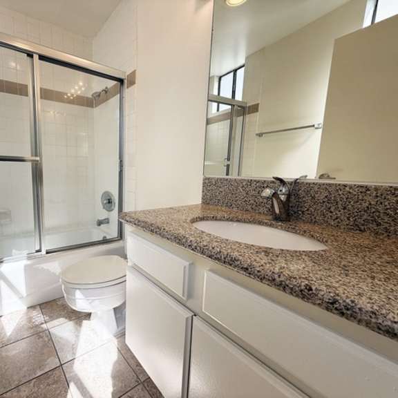 Thumbnail 12 of 18 A bathroom with a toilet, sink, and shower.