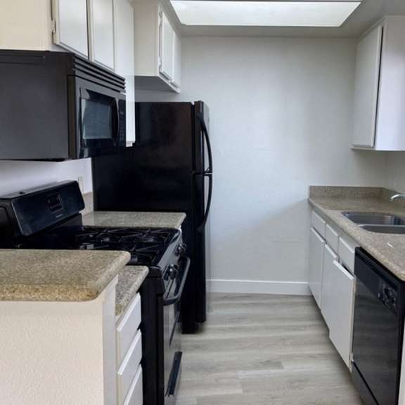 Thumbnail 8 of 27 A kitchen with black appliances and white cabinets.
