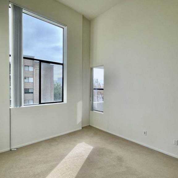 Thumbnail 2 of 27 A room with a large window and a carpeted floor.