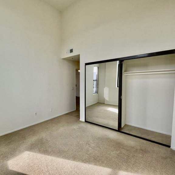 Thumbnail 7 of 27 A room with a carpeted floor and a large mirror on the wall.