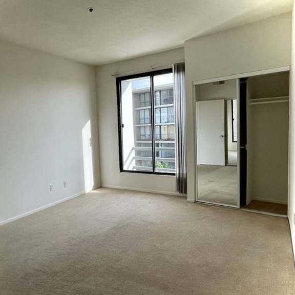 Thumbnail 9 of 27 A spacious, empty room with a large window and sliding glass doors.