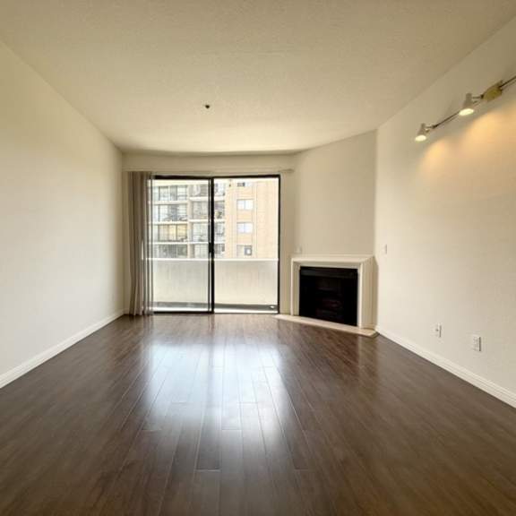 Thumbnail 5 of 27 A room with a fireplace and a large window with a view of a building.