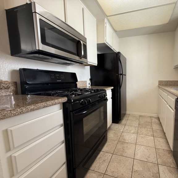 Thumbnail 12 of 27 A kitchen with black appliances and white cabinets.