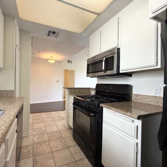 Thumbnail 16 of 27 A kitchen with black and white appliances and a granite counter.