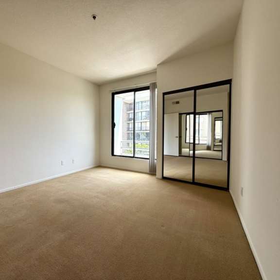 Thumbnail 23 of 27 A room with a carpeted floor and a sliding glass door.