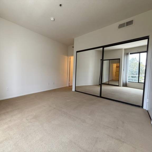 Thumbnail 25 of 27 A spacious room with a carpeted floor and a sliding glass door.