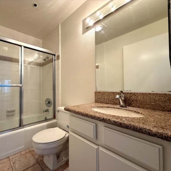Thumbnail 14 of 27 A bathroom with a toilet, sink, and shower.