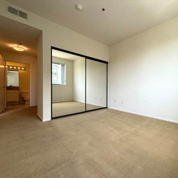Thumbnail 24 of 27 A room with a carpeted floor and a sliding glass door.