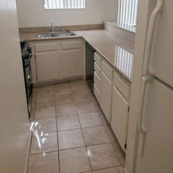 Thumbnail 2 of 9 A kitchen with white appliances and cabinets.
