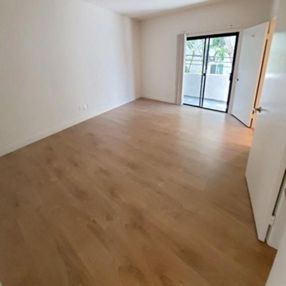 Thumbnail 8 of 9 A room with wooden flooring and a sliding glass door.
