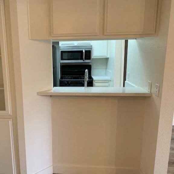 Thumbnail 2 of 10 A kitchen with white cabinets and a microwave oven.