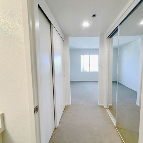 Thumbnail 13 of 31 A hallway with a white door and a mirror on the wall.