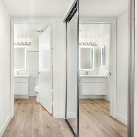 Thumbnail 6 of 28 A white bathroom with a toilet, sink, and mirror.