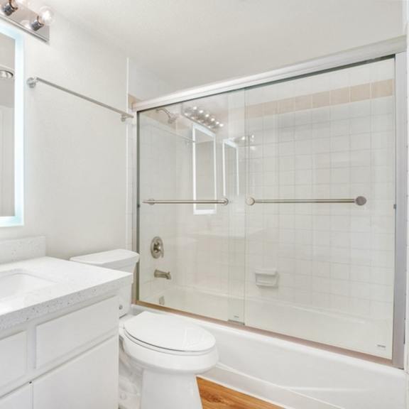 Thumbnail 14 of 28 A white bathroom with a toilet, sink, and shower.