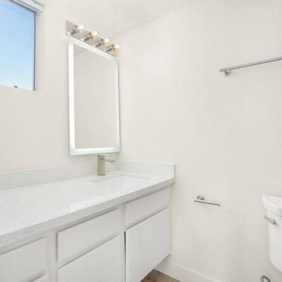 Thumbnail 19 of 28 A white bathroom with a large mirror and a white tub.