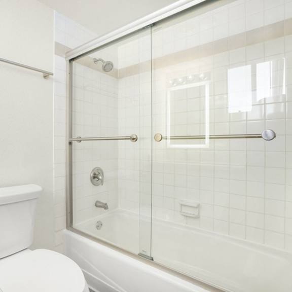Thumbnail 20 of 28 A white toilet is next to a glass shower door.