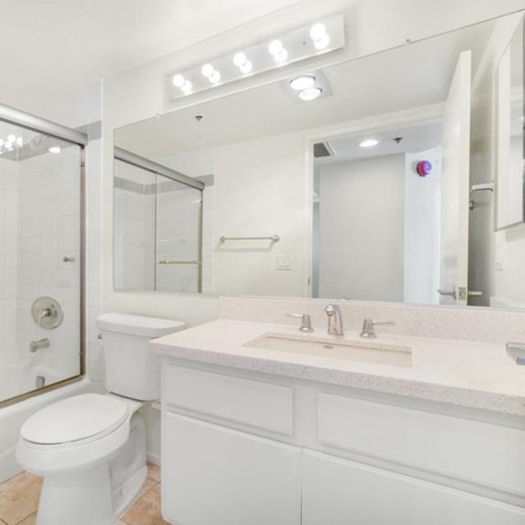Thumbnail 6 of 28 A white bathroom with a toilet, sink, and mirror.