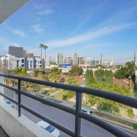 Thumbnail 2 of 28 A balcony overlooks a cityscape with buildings and palm trees.