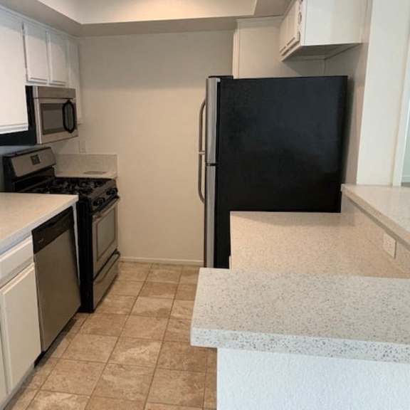 Thumbnail 3 of 16 A kitchen with black appliances and white cabinets.