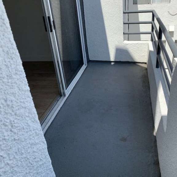 Thumbnail 6 of 16 A balcony with a glass door and a metal railing.
