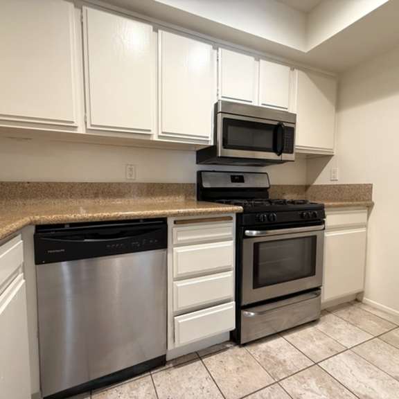 Thumbnail 7 of 53 A kitchen with white cabinets and a granite countertop.