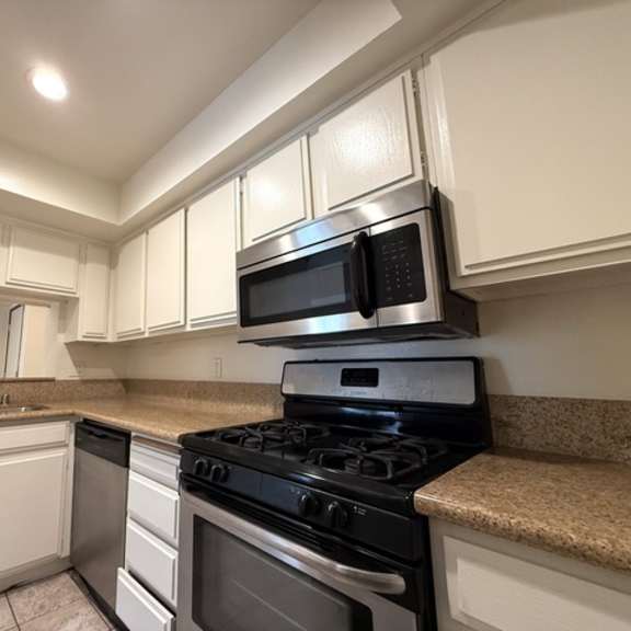 Thumbnail 4 of 53 A kitchen with black appliances and white cabinets.