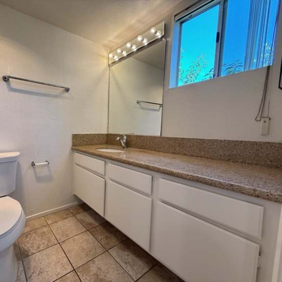 Thumbnail 3 of 53 A white toilet in a bathroom with a counter and a mirror.