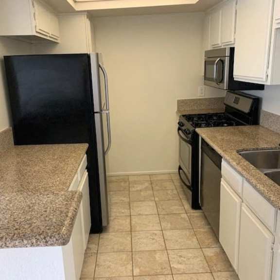 Thumbnail 11 of 18 A kitchen with black appliances and granite countertops.
