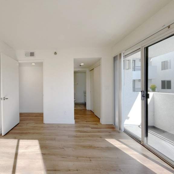 Thumbnail 4 of 17 A long hallway with a rug on the floor and a glass door on the right.