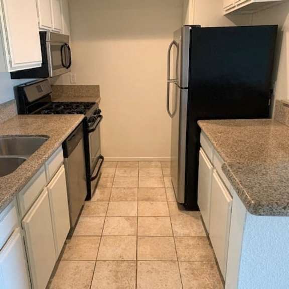 Thumbnail 21 of 24 A kitchen with black appliances and white cabinets.