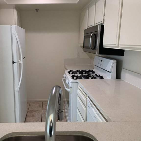 Thumbnail 3 of 8 A kitchen with a white refrigerator, stove, and microwave.