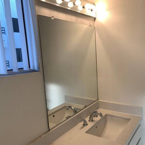 Thumbnail 8 of 8 A bathroom with a sink and mirror.