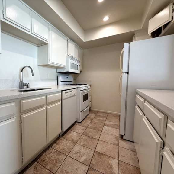 Thumbnail 8 of 24 A kitchen with white appliances and cabinets.