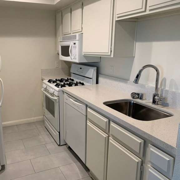 Thumbnail 4 of 13 A kitchen with a white refrigerator, microwave, and stove.