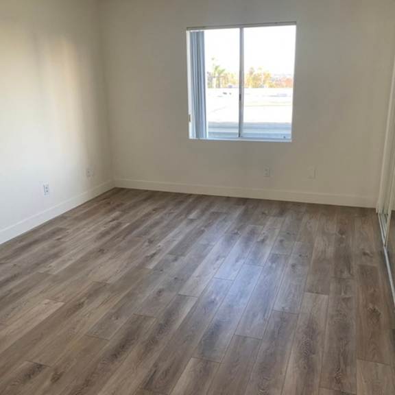 Thumbnail 10 of 13 A room with wooden flooring and a window overlooking a street.
