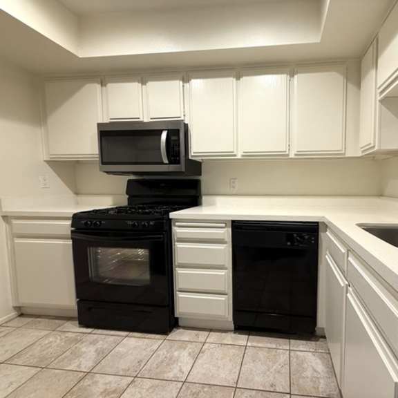 Thumbnail 12 of 28 A kitchen with black appliances and white cabinets.