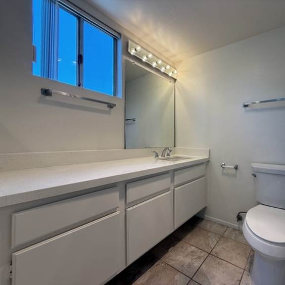 Thumbnail 28 of 28 A white bathroom with a toilet, sink, and mirror.
