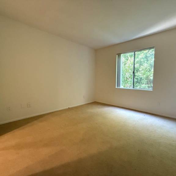 Thumbnail 27 of 28 A room with a window and a carpeted floor.