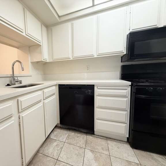 Thumbnail 25 of 53 A kitchen with black appliances and white cabinets.