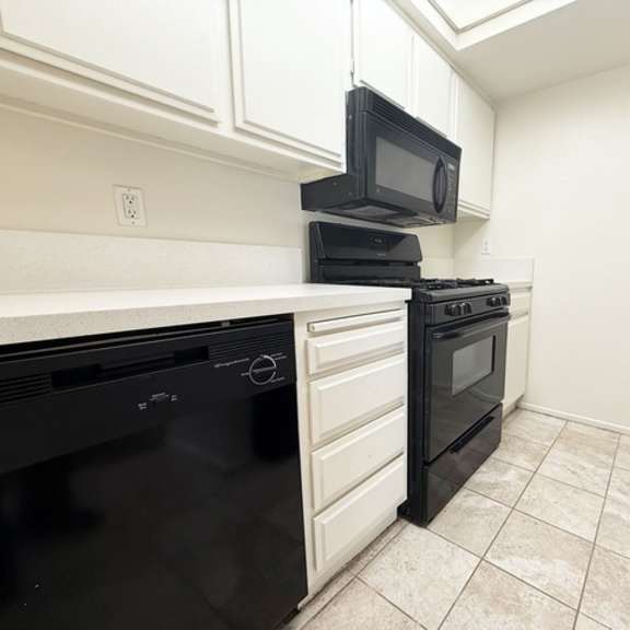 Thumbnail 31 of 53 A black oven is on the left side of a white countertop.