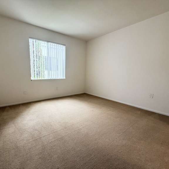 Thumbnail 34 of 53 A room with a carpeted floor and a window with blinds.
