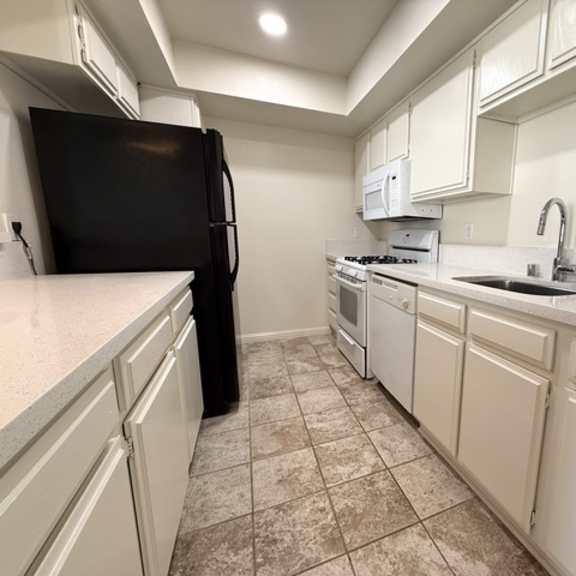 Thumbnail 9 of 15 A kitchen with black appliances and white cabinets.