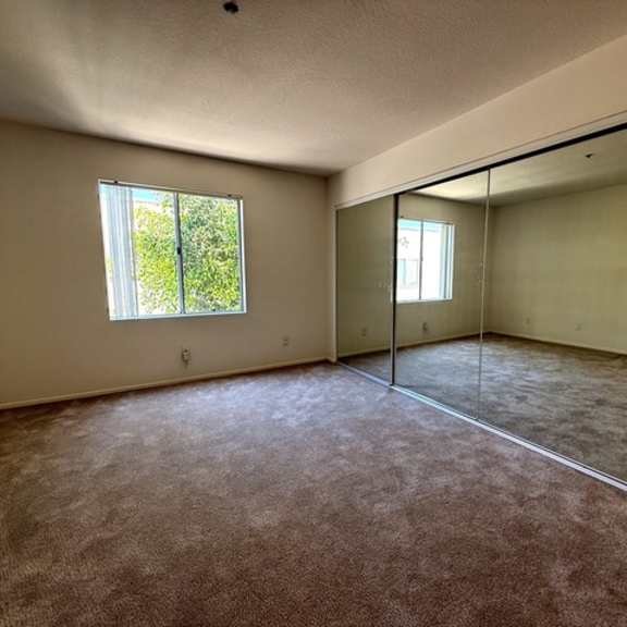 Thumbnail 4 of 15 A room with a carpeted floor and a large window.