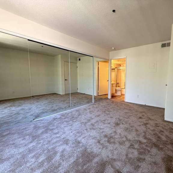 Thumbnail 7 of 15 A room with carpeted floor and a doorway leading to another room.