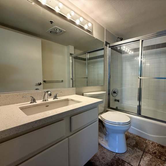 Thumbnail 11 of 15 A white toilet sits in a bathroom with a walk-in shower.