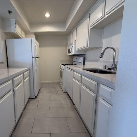 Thumbnail 8 of 13 A kitchen with white appliances and cabinets.