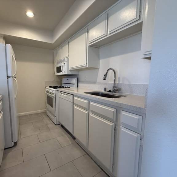 Thumbnail 12 of 13 A kitchen with white appliances and cabinets.