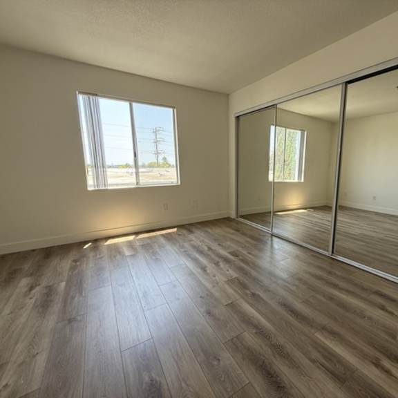 Thumbnail 6 of 13 A room with wooden flooring and a large window.